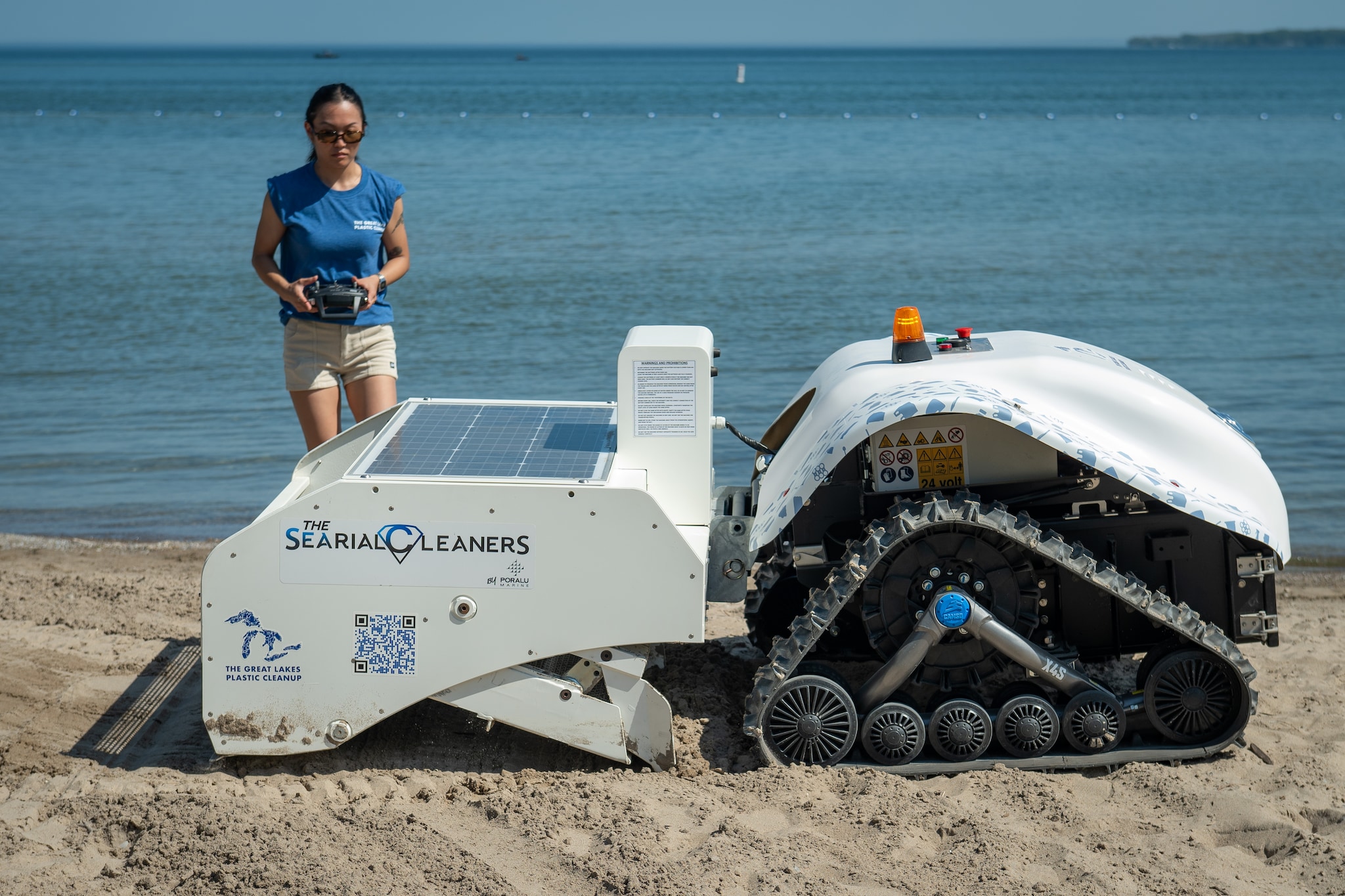 a woman operating a beach cleaning machine with a remote control
