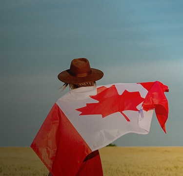 Person wrapped in a Canadian flag outdoors.