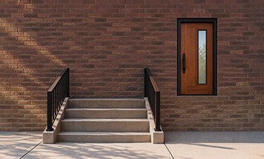 Concrete steps leading to a wooden door in a brick wall